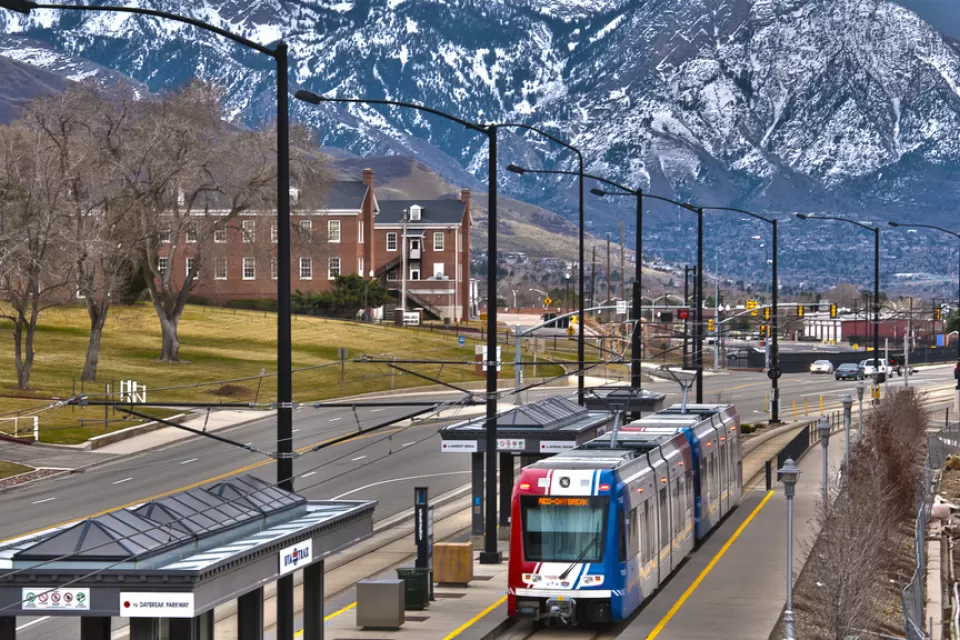 trax light rail train in foreground, snow-covered mountains in background